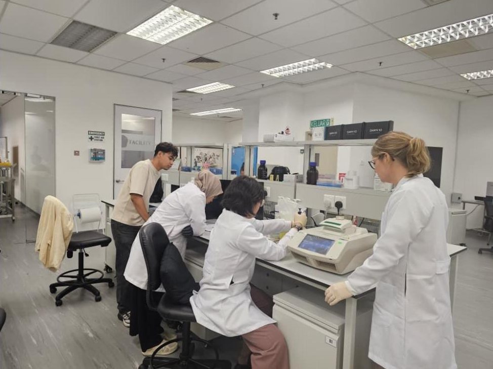 Scientists in white coats running a screening kit at the bench in the Arcadia laboratory